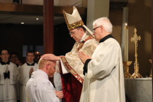 Bishop Thomas J. Olmsted imposes hands on Deacon Keith Kenney, ordaining him to the priesthood.