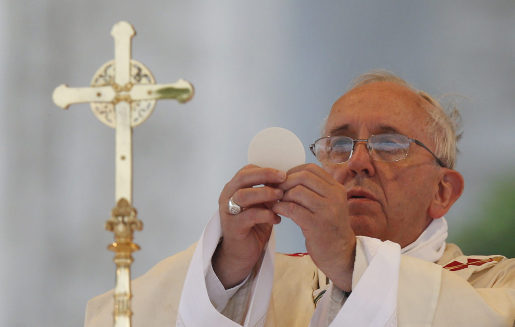 Pope Francis elevates the Eucharist as he celebrates Mass on the feast of Corpus Christi outside the Basilica of St. John Lateran in Rome June 19. (CNS photo/Paul Haring) 