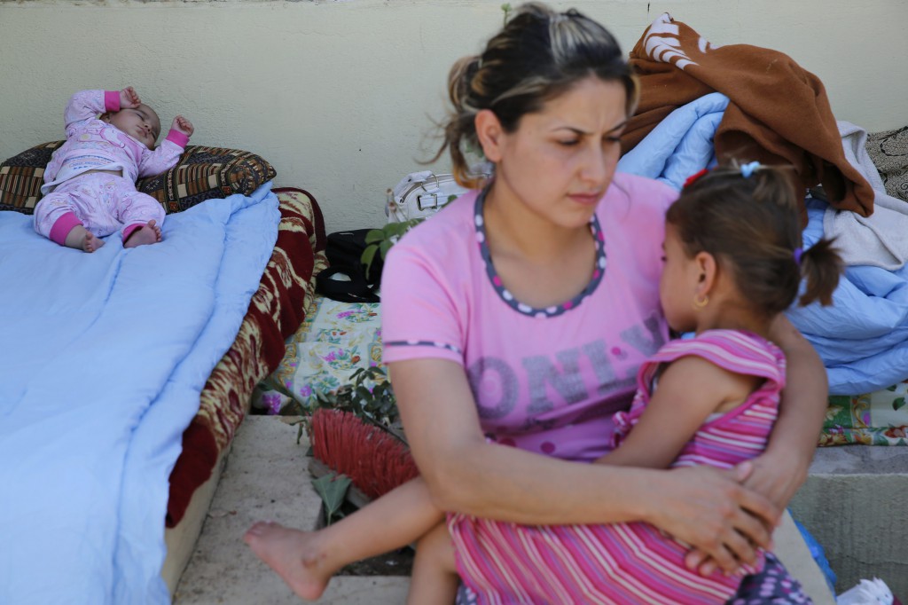 A Christian woman who fled from the violence in Mosul, Iraq, holds her daughter as her baby sleeps June 27 at a shelter in Irbil, Iraq. Chaldean Catholic Patriarch Louis Sako of Baghdad said the city of Mosul "is almost empty of Christians." (CNS photo/Ahmed Jadallah, Reuters)