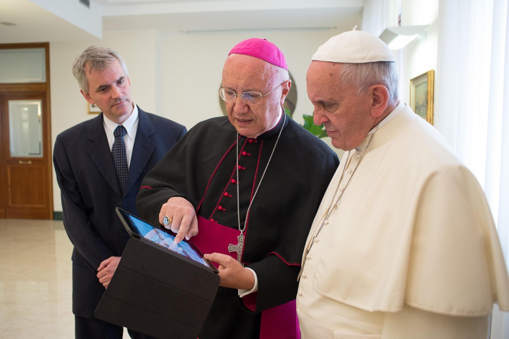 Archbishop Claudio Celli, president of the Pontifical Council for Social Communications, center, shows Pope Francis news on a tablet during a meeting at the Vatican July 7. (CNS photo/L'Osservatore Romano via Reuters)