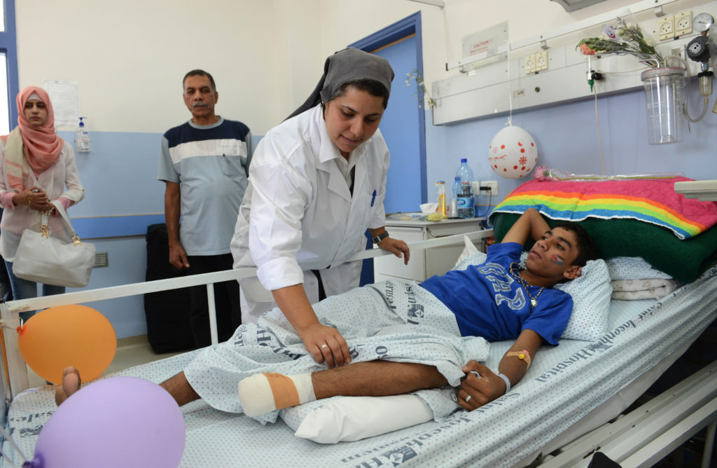 Sister Muna Totah, a member of the Sisters of St. Joseph of the Apparition, works on Karim Nofal, 15, of Gaza, at St. Joseph Hospital in Jerusalem July 30. The teenager is one of 23 Gaza patients being treated at the hospital, which specializes in head- and chest-trauma wounds. (CNS photo/Debbie Hill)