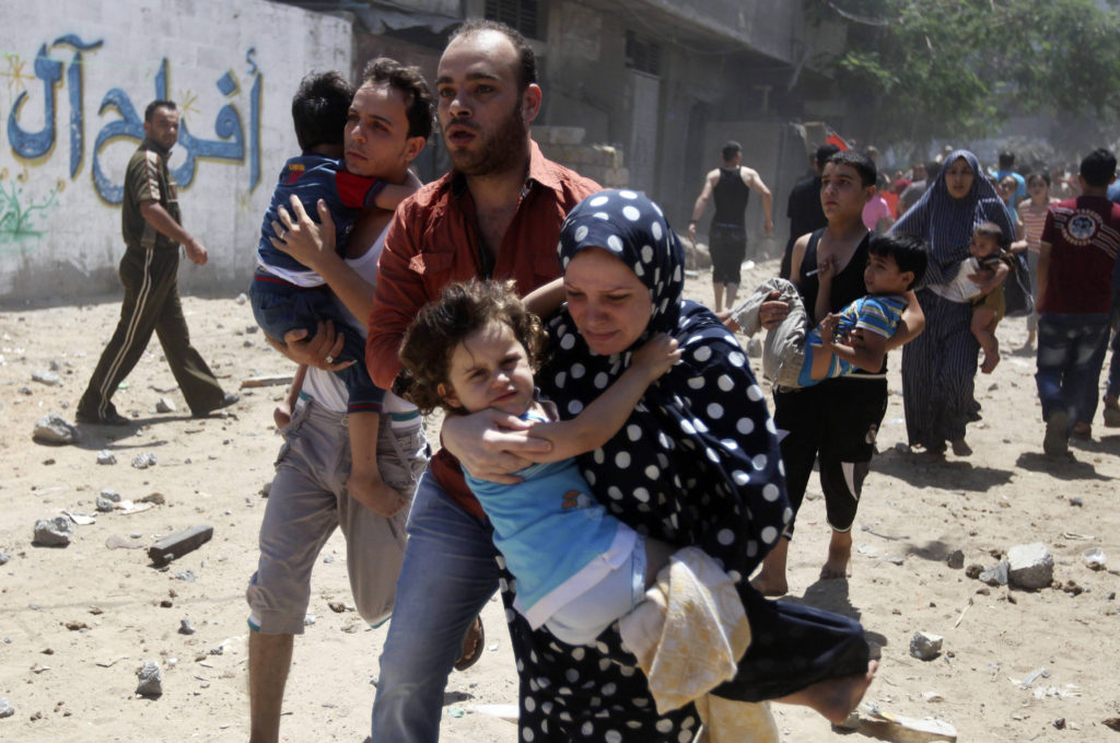 Palestinians run following what police said was an Israeli airstrike on a house in Gaza City July 9. The Israeli army intensified its offensive on the Hamas-run Gaza Strip, striking Hamas sites and killing dozens of people in a military operation it says is aimed at quelling rocket fire against Israel. (CNS photo/Majdi Fathi, Reuters)  