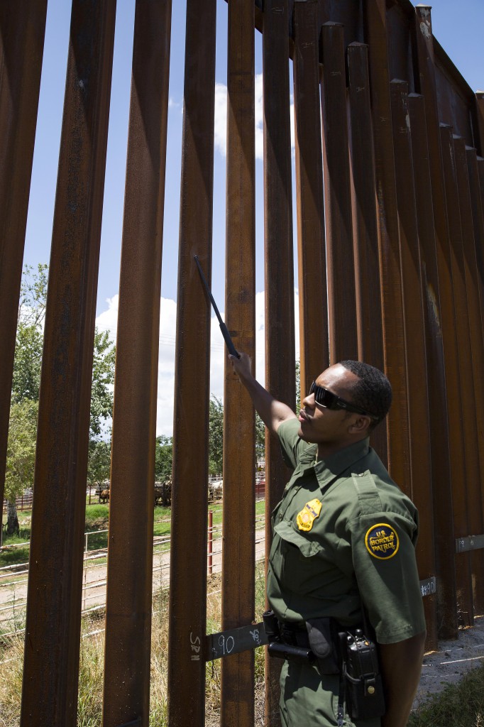 U.S. Border Patrol Agent Bryan Flowers points to an area on the steel-slat border fence west of Nogales, Ariz., July 16. Flowers said that fencing along the international border serves as an obstacle to unlawful crossings, but it "can't stop a person's will to cross if that's what they've decided to do." (CNS photo/Nancy Wiechec)