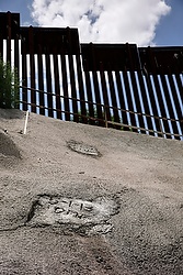 A date marks the exit of a former secret underground tunnel near the DeConcini port of entry in Nogales, Ariz., in this July 16 photo. The marking was put there last year on the day U.S. Customs and Border Protection sealed the tunnel that had been used to move narcotics and people into the U.S. Seen in the background is the steel border fence. (CNS photo/Nancy Wiechec)