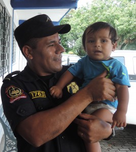A member of the Salvadoran national police is seen July 1 holding an infant who arrived back in San Salvador from Mexico. The number of children leaving the country is increasing dues to factors such as violence and a belief that minors will be granted asylum upon arriving in the United States. (CNS photo/David Agren)