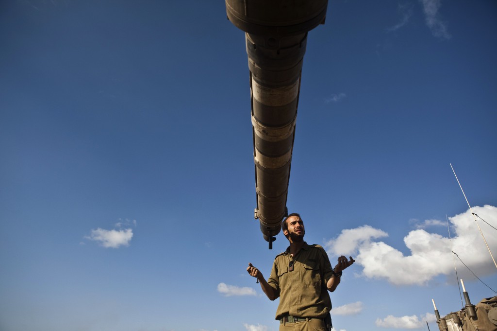 An Israeli soldier stands in front of the barrel of a tank at a military staging area outside the northern Gaza Strip July 14. Israel said it shot down a drone from Gaza a week into its offensive , the first reported deployment of an unmanned aircraft by Palestinian militants whose rocket attacks have been regularly intercepted. (CNS photo/Nir Elias, Reuters)