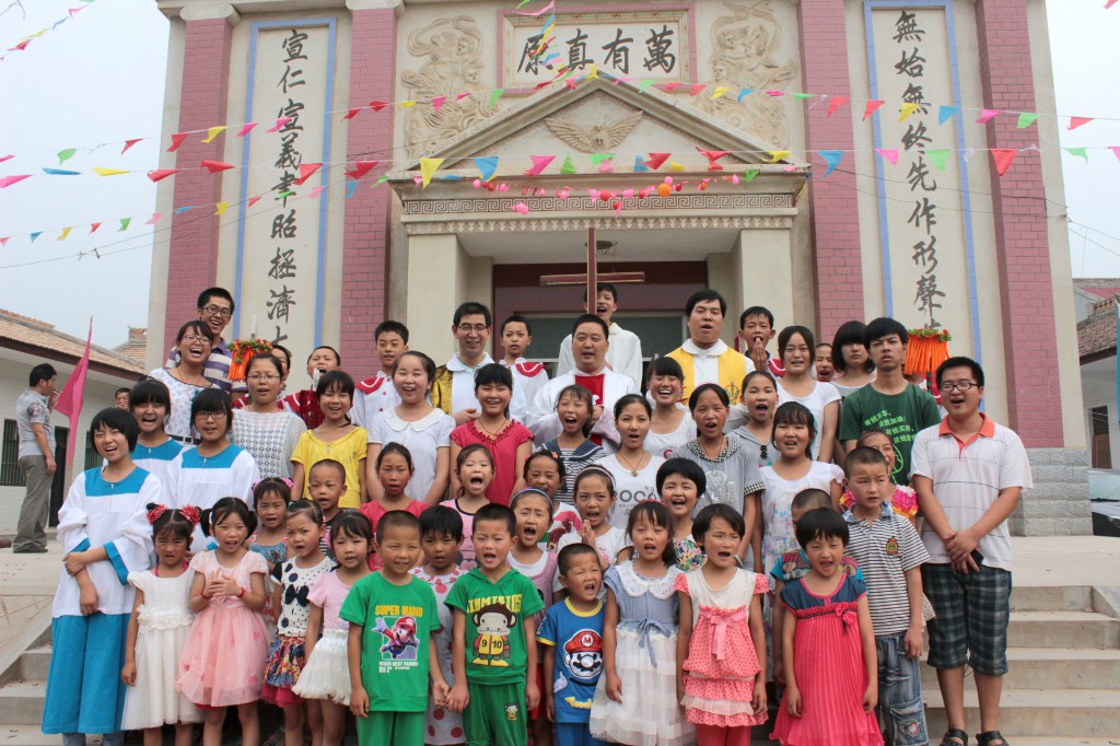 Children gather with parish priests for a photo on the steps of Sacred Heart of Jesus Church in the village of Fufengxian, in China's Shaanxi province, in late July 2013. The Catholic parish was marking its 17th anniversary in a region known for its apple groves. (CNS photo) ( 