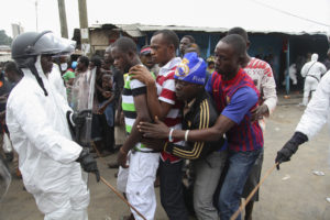 Liberian police in protective clothing control residents of Monrovia's West Point neighborhood waiting for food rations to be handed out Aug. 21. Church workers say hunger and panic are major problems in Liberia and Sierra Leone as neighborhoods are seal ed off in an effort to curb the spread of Ebola. (CNS photo/Ahmed Jallanzo, EPA)