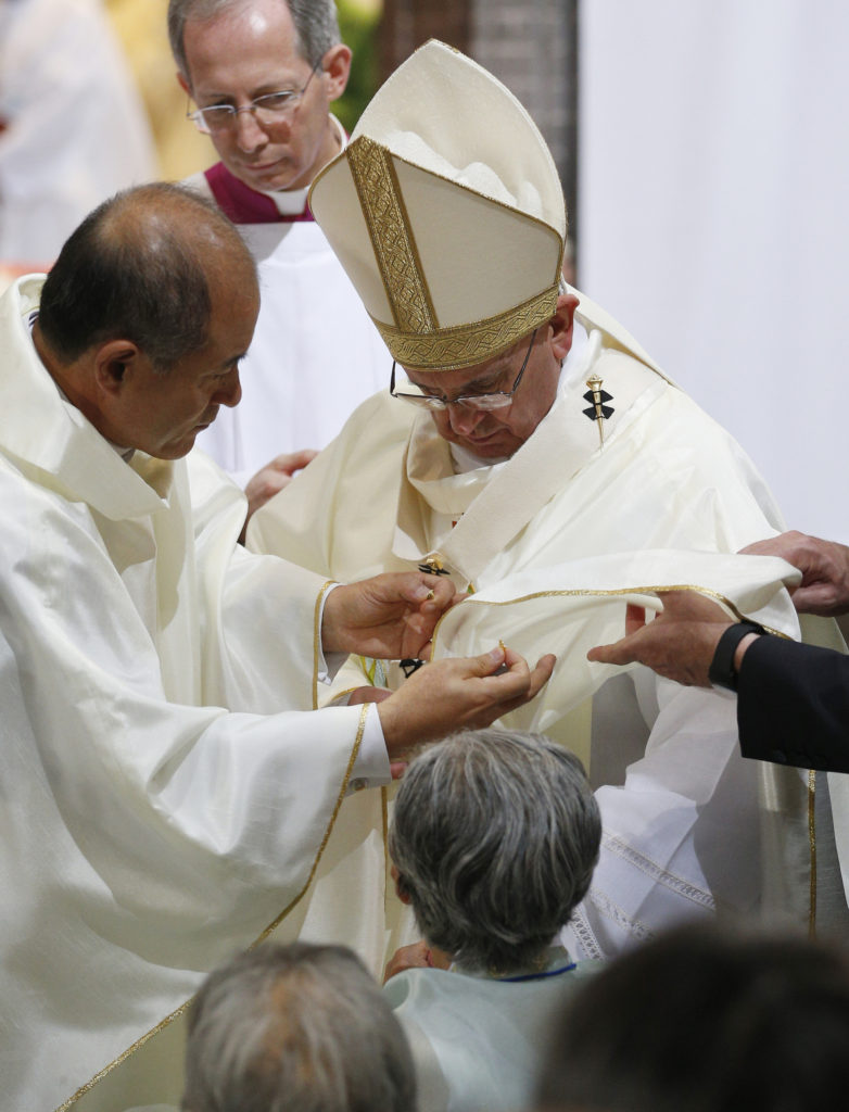 A clergyman places a butterfly pin on Pope Francis' vestment as he celebrates a Mass for peace and the reconciliation of North and South Korea at Myongdong Cathedral in Seoul, South Korea, Aug. 18. The pin symbolizes the cry for justice of World War II's comfort women, sex slaves for the Japanese. (CNS photo/Paul Haring) 