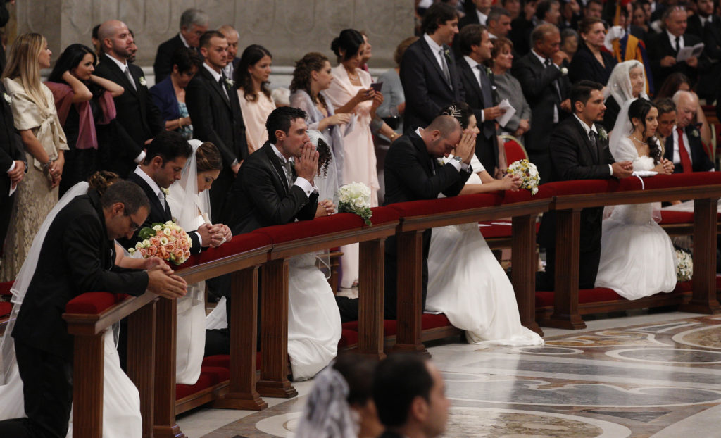 Newly married couples kneel as Pope Francis celebrates the marriage rite for 20 couples during a Mass in St. Peter's Basilica at the Vatican Sept. 14. (CNS photo/Paul Haring) See POPE-WEDDING Sept. 15, 2014.