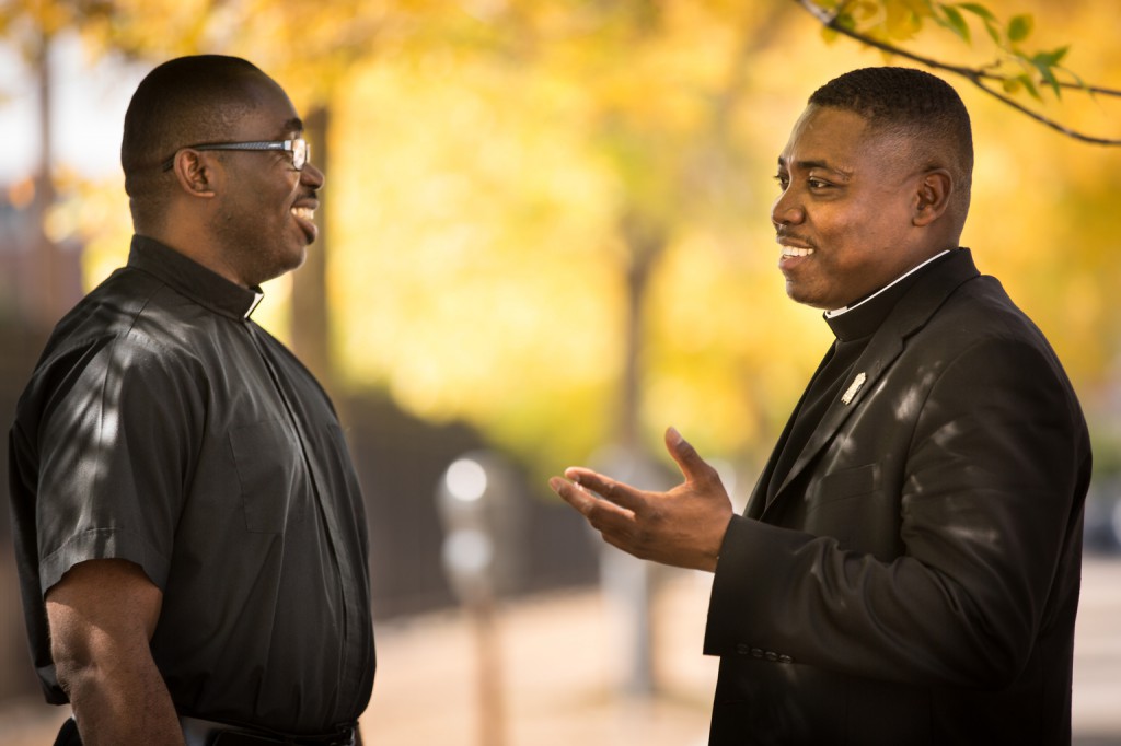 Fathers McDonald Nah and Urey Patrick Mark of Liberia chat outside St. Nicholas Church in St. Louis Sept. 25. Father Nah, a priest of the Archdiocese of Monrovia currently studying Catholic education administration at St. Louis University, is praying the Liberian people are just as resilient through the Ebola outbreak as they were following the country's civil war more than a decade ago. Father Mark, a member of the Society of the Divine Word, has been called back to his country. (CNS photo/Lisa Johnston, St. Louis Review)