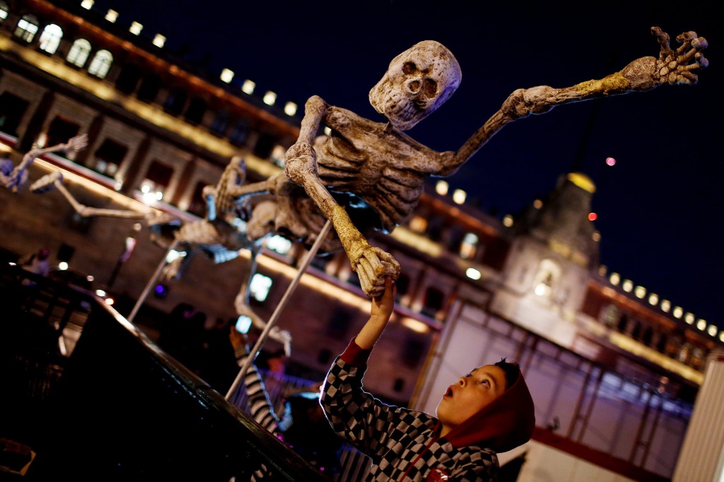 A child reacts while touching a skeleton model, which is part of an art installation to celebrate the Day of the Dead in Zocalo Square, Mexico City, Oct. 30. (CNS photo/Tomas Bravo, Reuters)