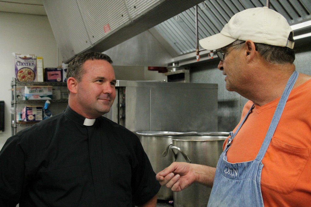 A volunteer and Holy Cross Father Tom Doyle inside the kitchen at André House Sept. 4. Fr. Doyle praised the effort of 10,000 volunteers who welcome André House guests each year. (Ambria Hammel/CATHOLIC SUN)