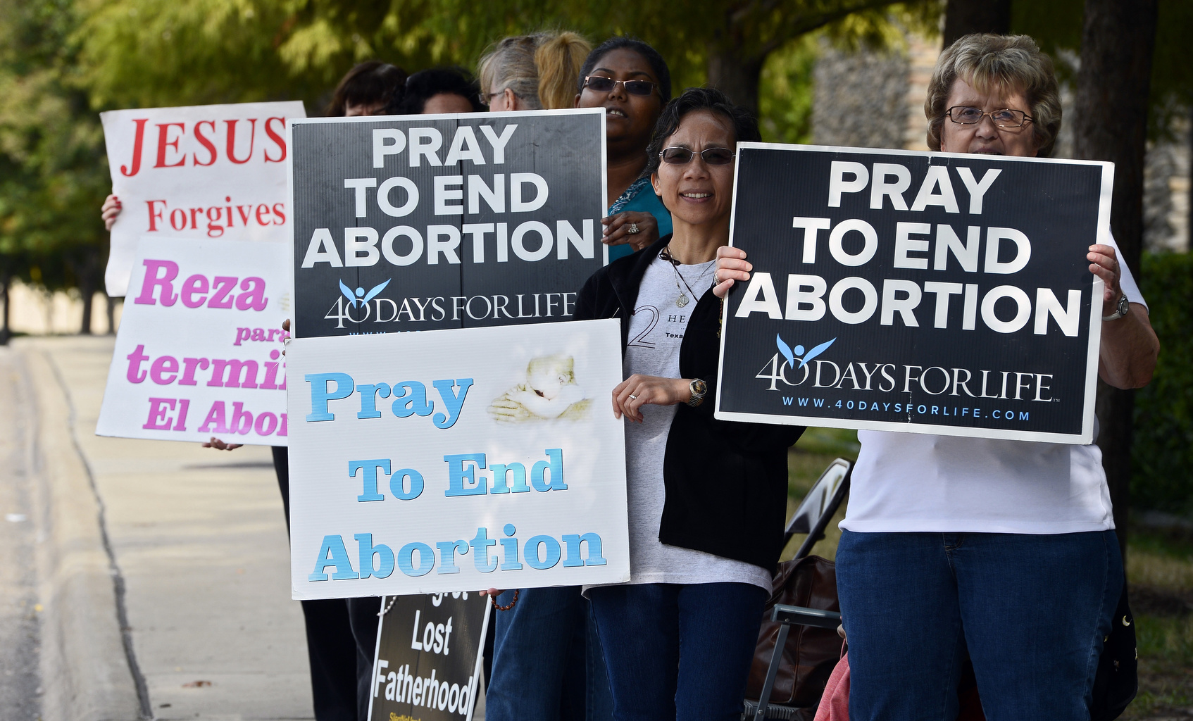 Pro-life supporters stand with signs along the street in front of Southwestern Women's Surgery Center in Dallas in 2013. The U.S. Supreme Court Oct. 14 placed a hold on a Texas state law requiring upgrades at abortion clinics and making clinic abortion doctors have admitting privileges at nearby hospitals. The court ruling allows the reopening of clinics that had closed because of the law. (CNS photo/Larry Smith, EPA) 