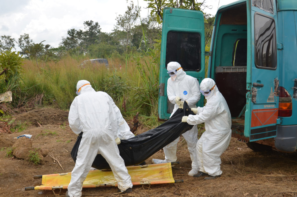 Health workers in protective gear take a body bag containing the highly contagious body of an Ebola victim out of a vehicle in preparation for burial at a cemetery in the Port Loko district in northern Sierra Leone. (CNS photo/Michael Stulman, courtesy Catholic Relief Services)