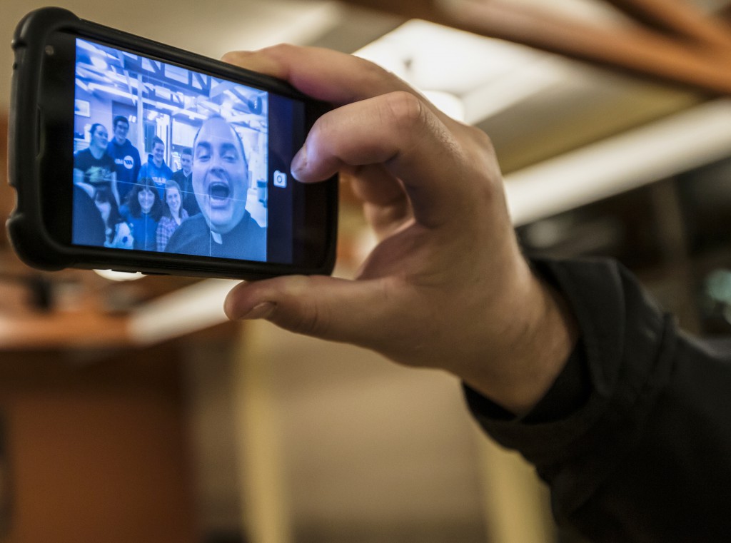 Father Jason Blahnik, director of the Catholic Campus Ministry at the University of Wisconsin-Oshkosh, takes a selfie with students at the Newman Center on campus Oct. 14. Father Blahnik said he's always looking for new ways to engage young people and attract them to his Catholic ministry. (CNS photo/ Jeannette Merten, The Compass) 