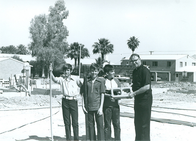 Msgr. McMahon and a St. Theresa youth shows one of the founding bricks used to build the school in 1974. A year later, a new church and parish center was dedicated. (photo courtesy of Diocese of Phoenix Office of Archives)