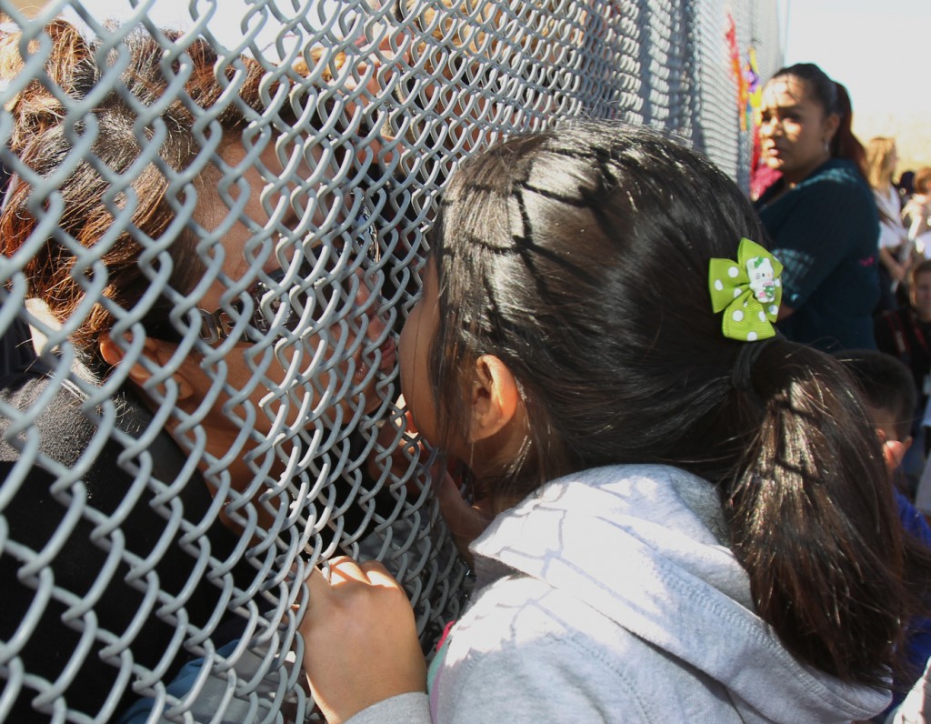 Jocelyn Lara, on the New Mexico side of the U.S.-Mexico border, kisses her mother, Trinidad Acahua, before Mass Nov. 22 in Sunland Park, N.M. Jocelyn and her sister, Yoryet, were separated from their mother after Acahua was deported seven years ago for being unable to show that she worked in the United States legally. (CNS photo/Bob Roller)  