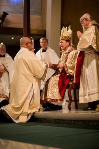Newly ordained Deacon Frank Nevarez receives the Book of the Gospels from Bishop Thomas J. Olmsted Nov. 8 and promises to believe what it teaches and practice what he preaches. (Billy Hardiman/CATHOLIC SUN)