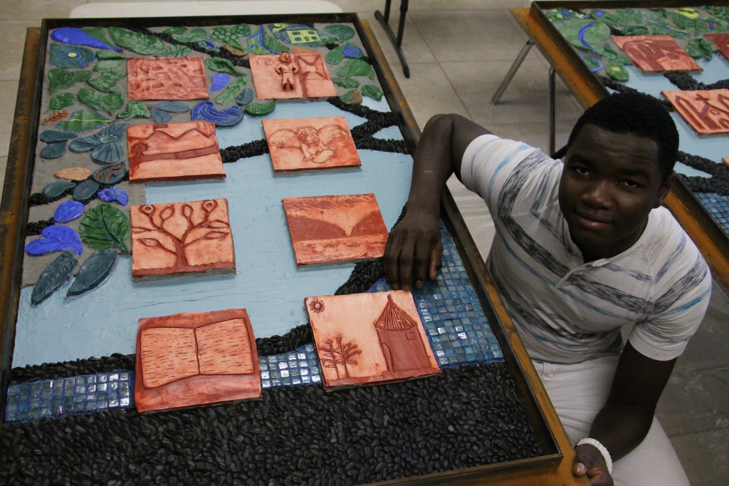 Ishak, a 19-yearold refugee from South Sudan, was one of 24 refugee youth whose carved tiles depict their memory or idea of a  safe place. (Ambria Hammel/CATHOLIC SUN)