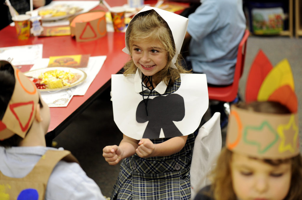Kindergarten students, including Rachael Henry, center, dressed as Pilgrims and Native Americans, take part in a special Thanksgiving feast Nov. 19 at St. Joseph School in Penfield, N.Y.  The holiday, celebrated Nov. 22 this year, commemorates the Pilgrims' celebration of a good harvest in 1621. (CNS photo/Mike Crupi, Catholic Courier)  