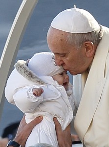 Pope Francis kisses a baby during his general audience in St. Peter's Square at the Vatican Dec. 10. (CNS photo/Paul Haring)