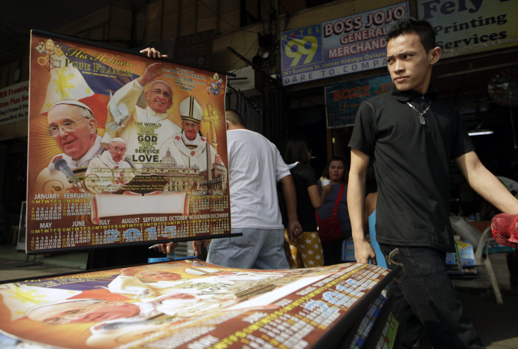 A man in Manila, Philippines, Dec. 19, walks past a 2015 calendar with Pope Francis pictures as part of the preparations for the pope's visit. Pope Francis is scheduled to visit the Philippines Jan. 15-19. (CNS photo/Ritchie B. Tongo, EPA)