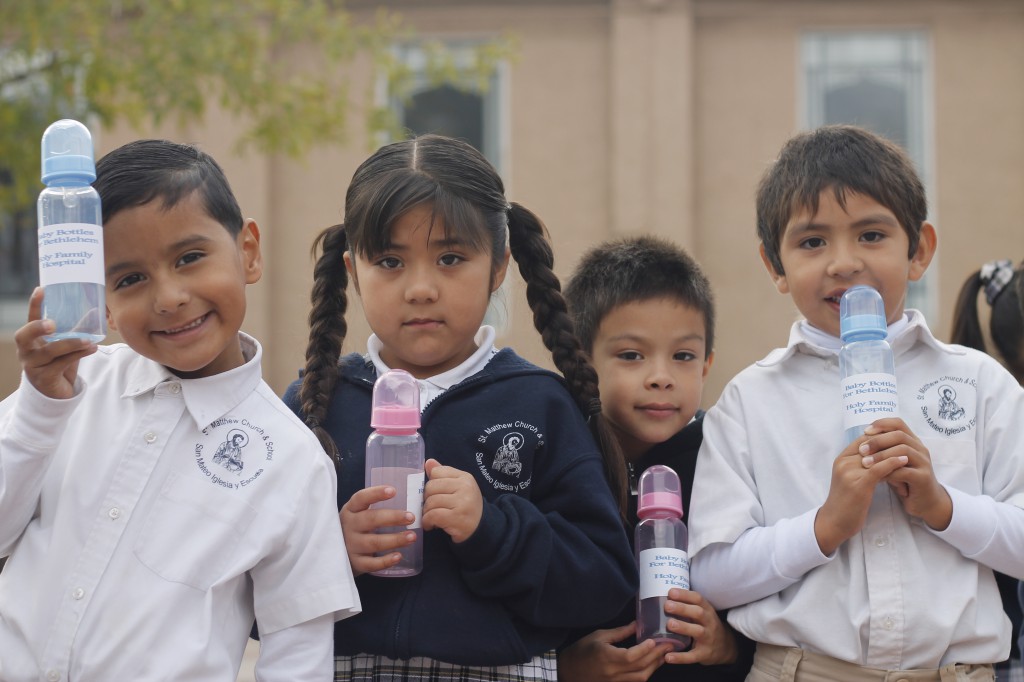  Kindergartners at St. Matthew School show off baby bottles Dec. 3. Students throughout the diocese are filling them with funds for the “Birthplace of Hope.” (Ambria Hammel/CATHOLIC SUN)