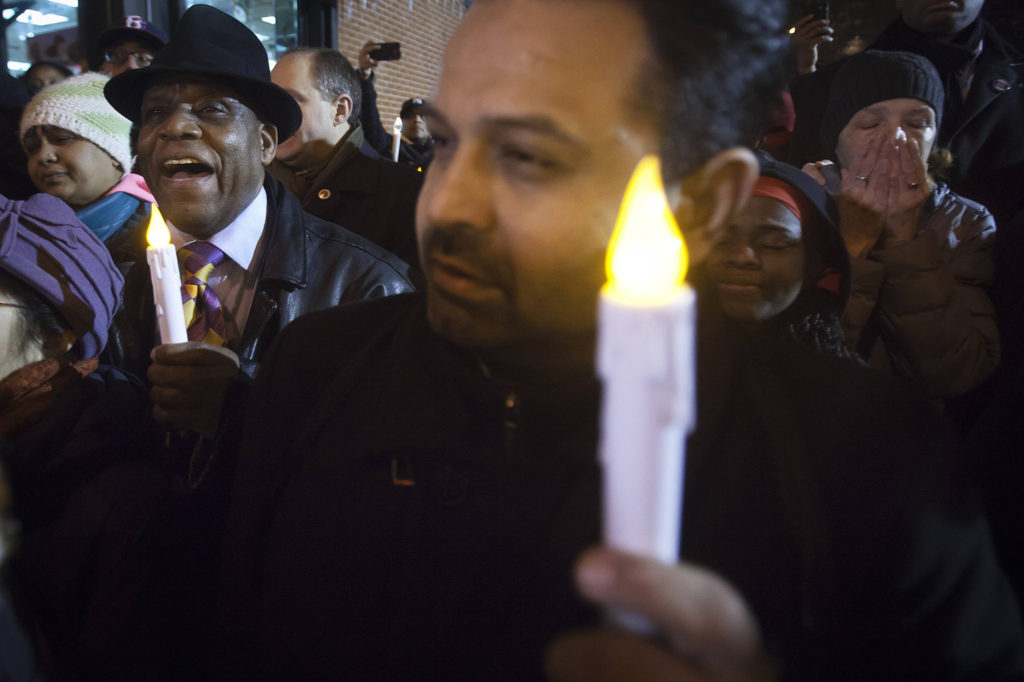 People sing as they take part in  prayer vigil at site where two NYPD officers were shot in Brooklyn borough of New York