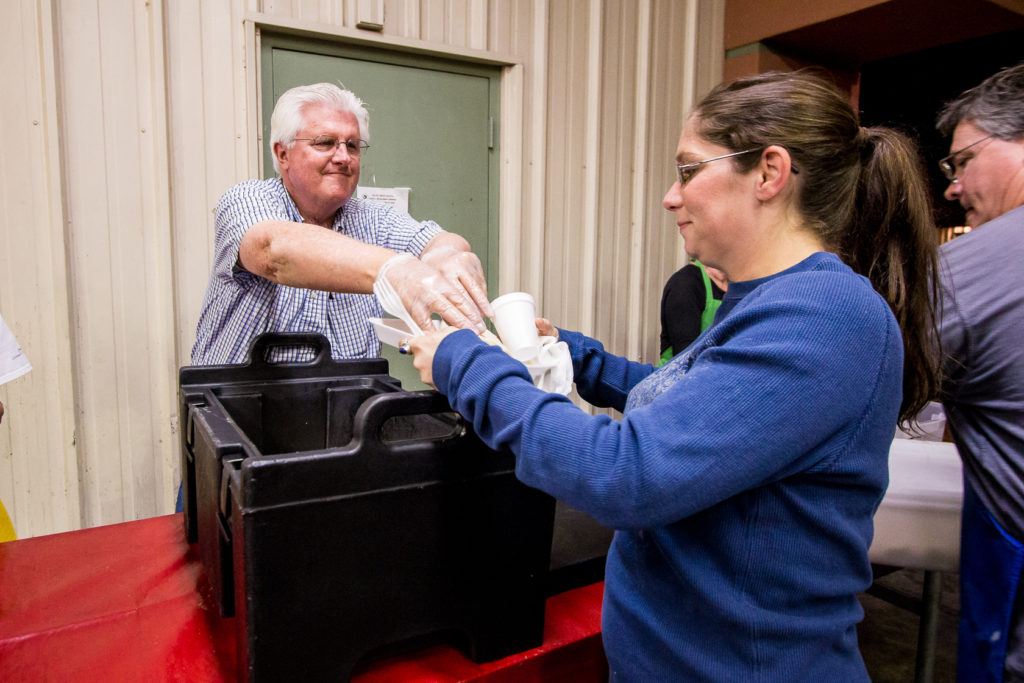 A volunteer serves dinner to a guest at Paz de Cristo in Mesa. Free meals and other services are available at the facility as well as at Andre House and the five St. Vincent de Paul dining rooms. (Billy Hardiman/CATHOLIC SUN)