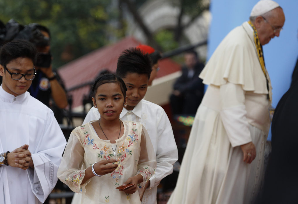 Glyzelle Palomar, 12, and Jun Chura, 14, two former street children, walk to their seats after greeting Pope Francis during a meeting with young people at the University of Santo Tomas in Manila, Philippines, Jan. 18. (CNS photo/Paul Haring)