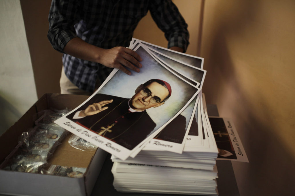 A volunteer holds posters of slain Salvadoran Archbishop Oscar Romero at a church in San Salvador Feb. 3. (CNS photo/Jose Cabezasi, Reuters)  