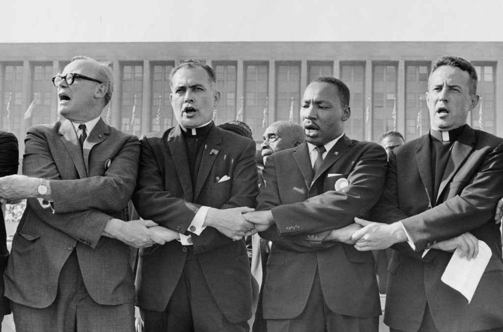 Holy Cross Father Theodore Hesburgh, second from left, joins hands with with the Rev. Martin Luther King Jr., the Rev. Edgar Chandler and Msgr. Robert J. Hagarty of Chicago, far right, in 1964 at the Illinois Rally for Civil Rights in Chicago's Soldier Field. Father Hesburgh, former president of the University of Notre Dame in Indiana, died Feb. 26 at age 97 in the Holy Cross House adjacent to the university. (CNS photo/courtesy University of Notre Dame) See OBIT-HESBURGH and HESBURGH-BYRON Feb. 27, 2015, and HESBURGH-WAKE March 4, 2015.