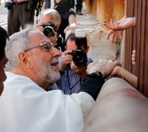 Bishop Gerald F. Kicanas of Tucson, Ariz., blesses people on the Mexican side as he distributes Communion through the border fence in Nogales, Ariz. in this April 2014 file photo. (CNS photo/Nancy Wiechec)