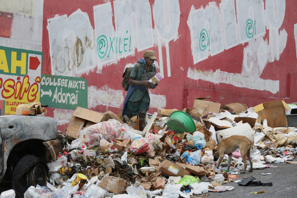 A woman and dog are seen amid garbage along a street in Port-au-Prince, Haiti, Feb. 9. Pope Francis feels a responsibility to remind Christians of their religious obligation to safeguard creation, beginning with human beings who are created in the image and likeness of God. (CNS photo/Bob Roller) 