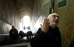 Passionist Father Francesco Guerra talks about artwork above the Holy Stairs as people pray on their knees at the Pontifical Sanctuary of the Holy Stairs in Rome March 10. Tradition maintains that Jesus climbed the stairs when Pilate brought him before the crowd. It's believed that Constantine's mother, St. Helen, brought the stairs to Rome from Jerusalem in 326. (CNS photo/Paul Haring)