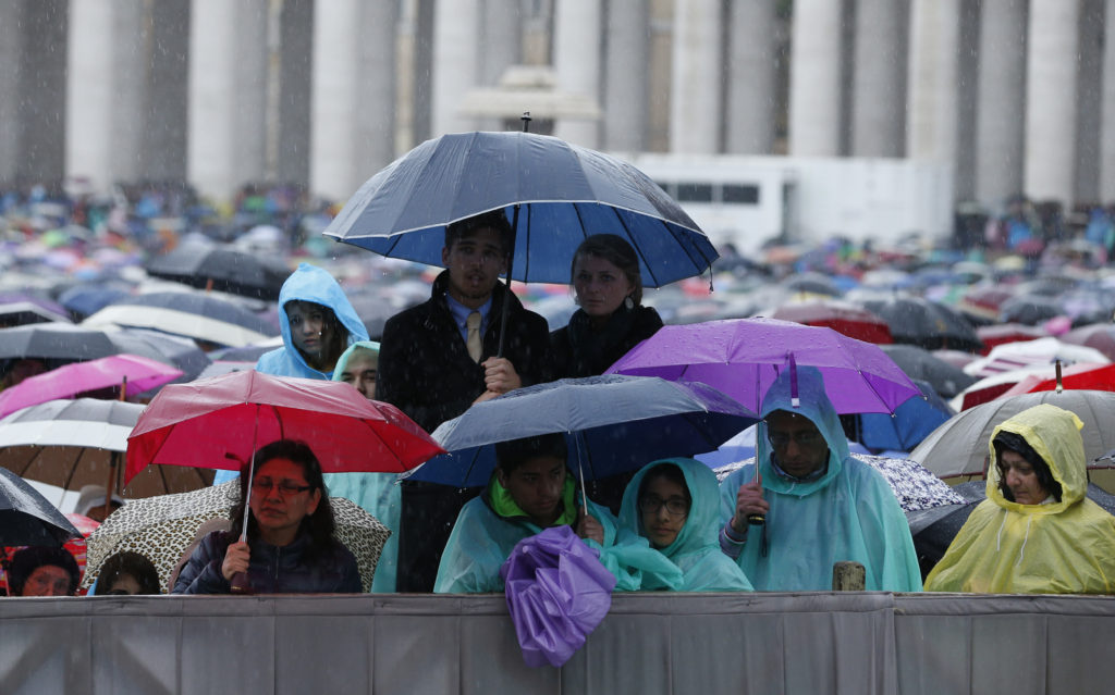 People huddle under umbrellas as they wait for the start of Pope Francis' celebration of Easter Mass in St. Peter's Square at the Vatican April 5. (CNS photo/Paul Haring)