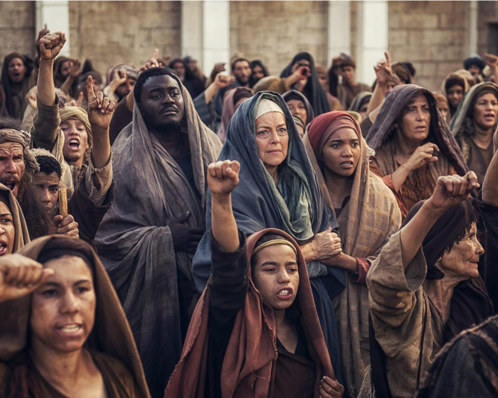 Standing in a crowd just behind a child with a raised fist are John (Babou Ceesay), Mary the mother of God (Greta Scacchi) and Mary Magdalene (Chipo Chung) in a scene from the 12-week miniseries "A.D.: The Bible Continues," which airs on NBC Sundays (CNS photo/courtesy Arenas Group)