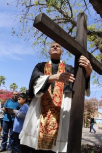 Fr. Rob Clements, director and pastor of the All Saints Newman Center in Tempe, holds the cross at the First Station of the Cross outside of ASU's interfaith chapel. The Good Friday Stations of the Cross at Arizona State University drew hundreds of students, adults and families April 3, 2015. It moved throughout campus and concluded atop "A" Mountain. (Ambria Hammel/CATHOLIC SUN)