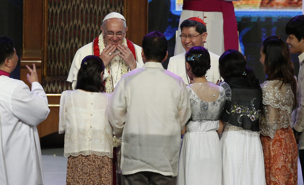 Pope Francis uses sign language to say thank you while meeting a deaf father and his family during an encounter with families in the Mall of Asia Arena in Manila, Philippines, Jan. 16. Also pictured is Cardinal Luis Antonio Tagle of Manila. (CNS photo/Paul Haring)