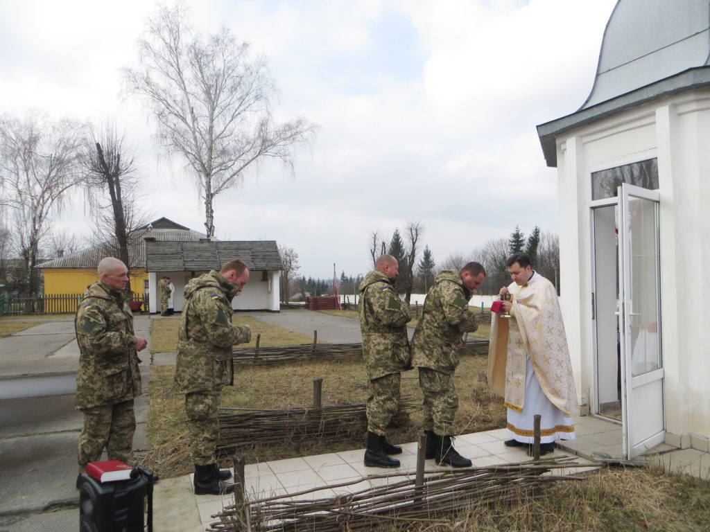 Fr. Taras Mykhalchuk gives holy Communion to Ukrainian soldiers in Yavoriv, Ukraine, in March. (CNS photo/courtesy Mariana Karapinka)