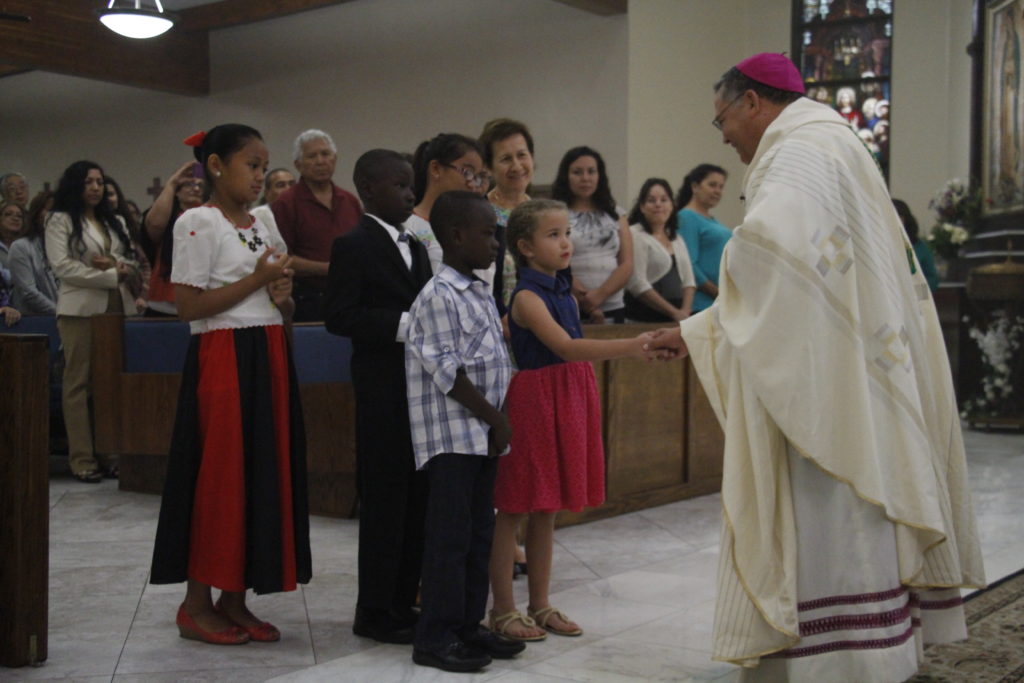 El Osbispo Auxiliar Eduardo A. Nevares saluda y bendice a niños de las 16 comunidades étnicos de la diócesis en el comienzo de la Misa de diversidad cultura diocesana el 25 de abril. (Ambria Hammel/CATHOLIC SUN)