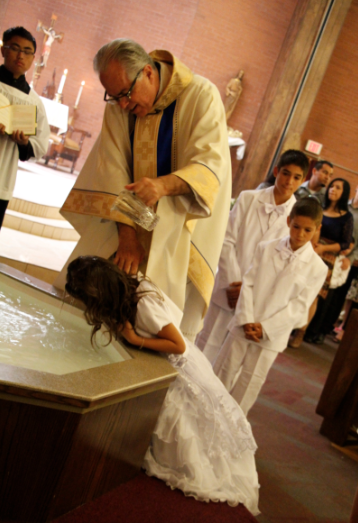  Fr. Mike Straley baptizes some of of the ___ children during a school Mass at Our Lady of Perpetual Help in Glendale April 16. (Ambria Hammel/CATHOLIC SUN)