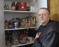 Franciscan Father John Luke Gregory, Santa Maria Parish priest and a native of Sheffeld, England, poses May 1 in front of the food pantry his parishioners stock for any needy people, including many refugees, who comes to the church's door in Rhodes, Greece. (CNS photo/Judith Sudilovsky) 