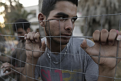 An Afghan refugee stands behind a fence at the yard of an abandoned hotel on the island of Kos, near the sea border with Turkey and Greece, May 6. (CNS photo/Yannis Kolesdis, EPA) 
