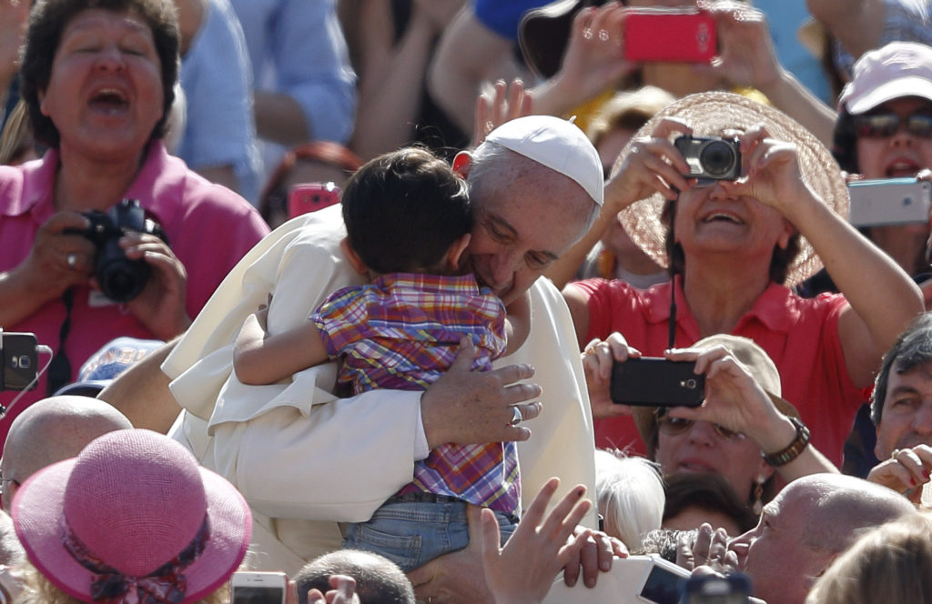 Pope Francis hugs a child as he arrives at the general audience in St. Peter's Square at the Vatican May 13. (CNS photo/Paul Haring) 