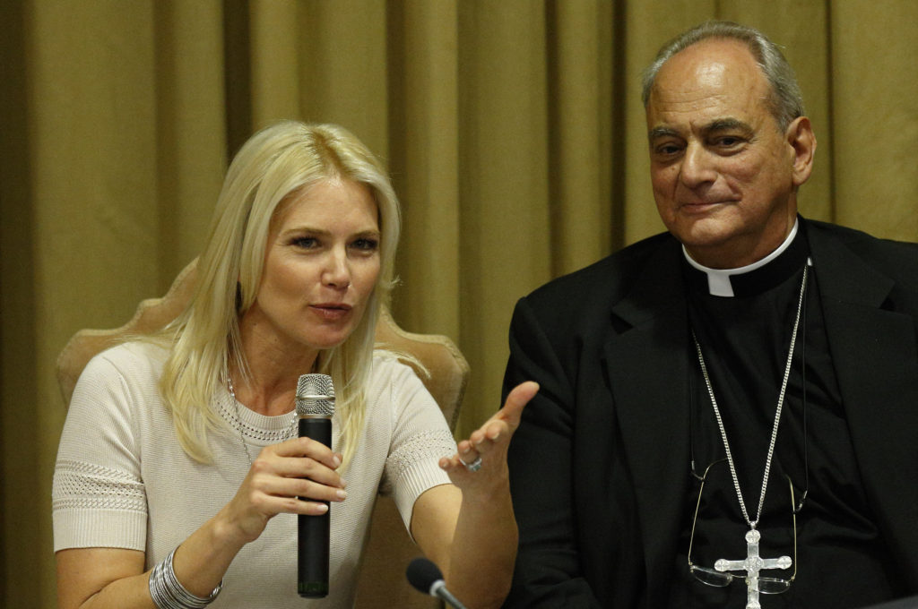 Argentinie model Valeria Mazza, serving as master of ceremonies, speaks during a workshop on climate change and human trafficking attended by mayors from around the world in the synod hall at the Vatican July 21. At right is Bishop Marcelo Sanchez Sorondo, chancellor of the Pontifical Academy of Sciences. Local government leaders were invited to the Vatican by the academy to sign a declaration recognizing that climate change and extreme poverty are influenced by human activity. They also pledged to pursue low impact development of cities. (CNS photo/Paul Haring)