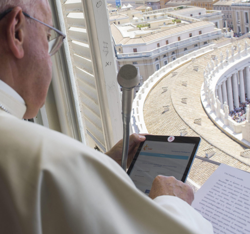 Pope Francis uses a tablet to officially open online registration for World Youth Day 2016 in Poland. He did this during the Angelus from the window of his studio overlooking St. Peter's Square at the Vatican July 26. (CNS photo/L'Osservatore Romano via EPA)