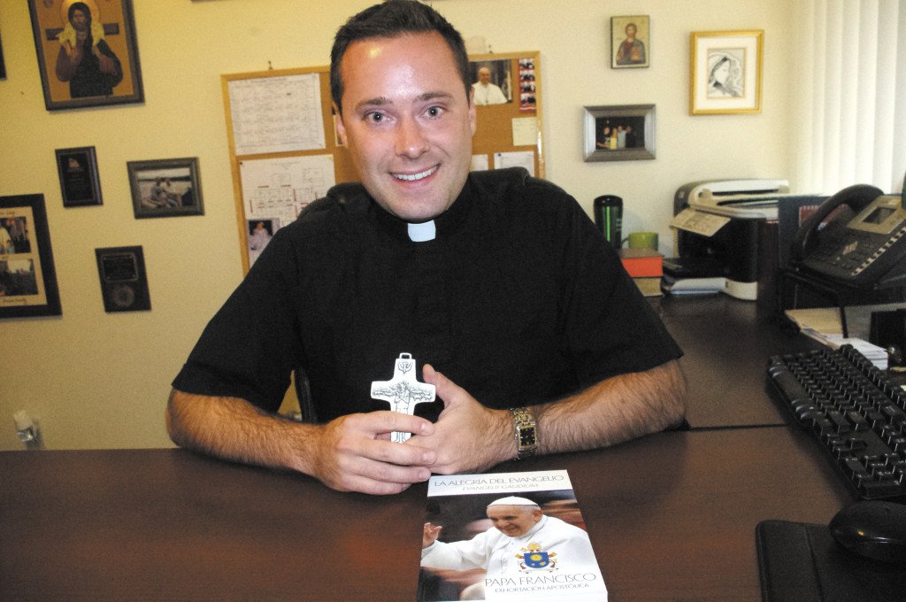 Fr. David Halm, CSC, ordained to the priesthood in April, holds a cross at his desk at St. John Vianney Parish in Goodyear. (Joyce Coronel/CATHOLIC SUN)