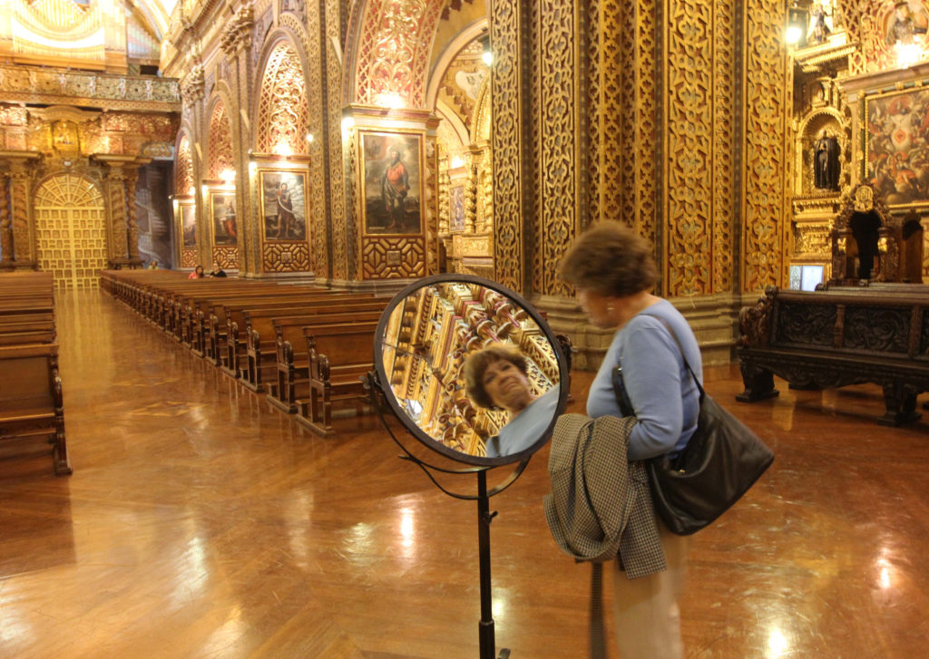 A visitor uses a mirror to take a closer look at the ornate architectural details of Quito's Iglesia de la Compania July 3. (CNS/Barbara Fraser) 